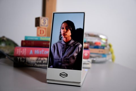 A Looking Glass Go display opened and freestanding on a desk. A portrait of a young, dark-skinned woman is on the screen.