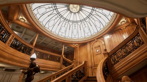 An interior recreation of the Titanic highlighting a grand staircase and balcony and a glass dome overhead.